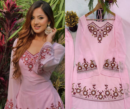 Baby Pink Heavy Faux Georgette Top Palazzo Set - outdoor garden full length standing model view showing complete set with V-neckline sunflower mirror embroidery, sheer puff sleeves with embroidery cuff, wide sunflower mirror embroidery hem border on top with gold lace trim, and wide-leg palazzo with matching embroidery hem border