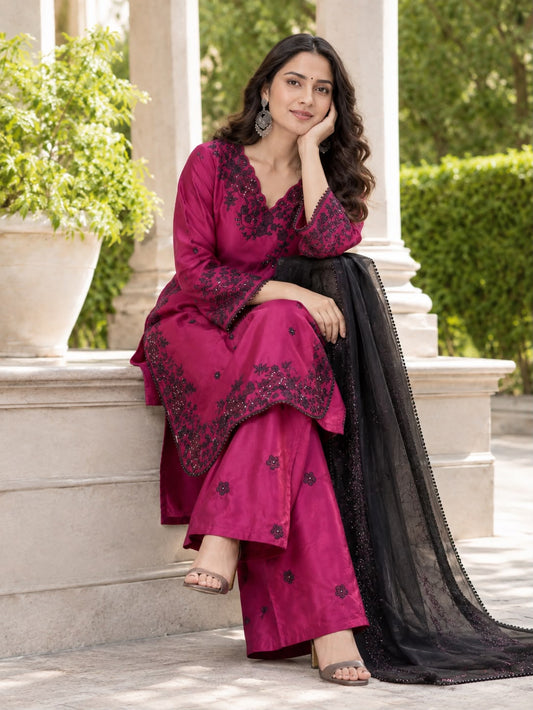 Deep Magenta Premium Crepe Palazzo Set - outdoor garden close-up portrait model showing V-neck black floral bouquet yoke embroidery with 3mm sequence, scattered black butti on magenta crepe body and black organza gold shimmer dupatta with pearl lace border draped over shoulder