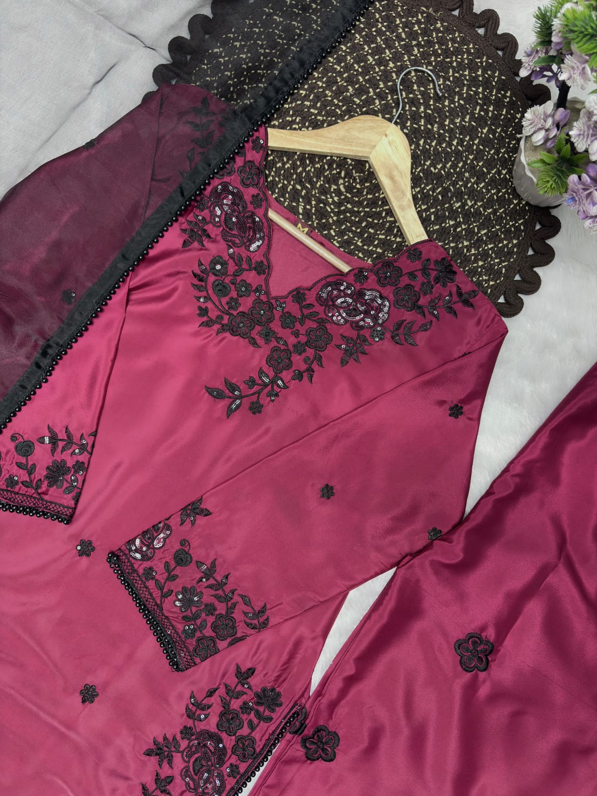 Deep Magenta Premium Crepe Palazzo Set - outdoor garden full length standing model front view showing complete set with V-neck black floral yoke, wide-leg magenta palazzo with scattered black butti and black organza dupatta with pearl lace border draped over arm in natural light