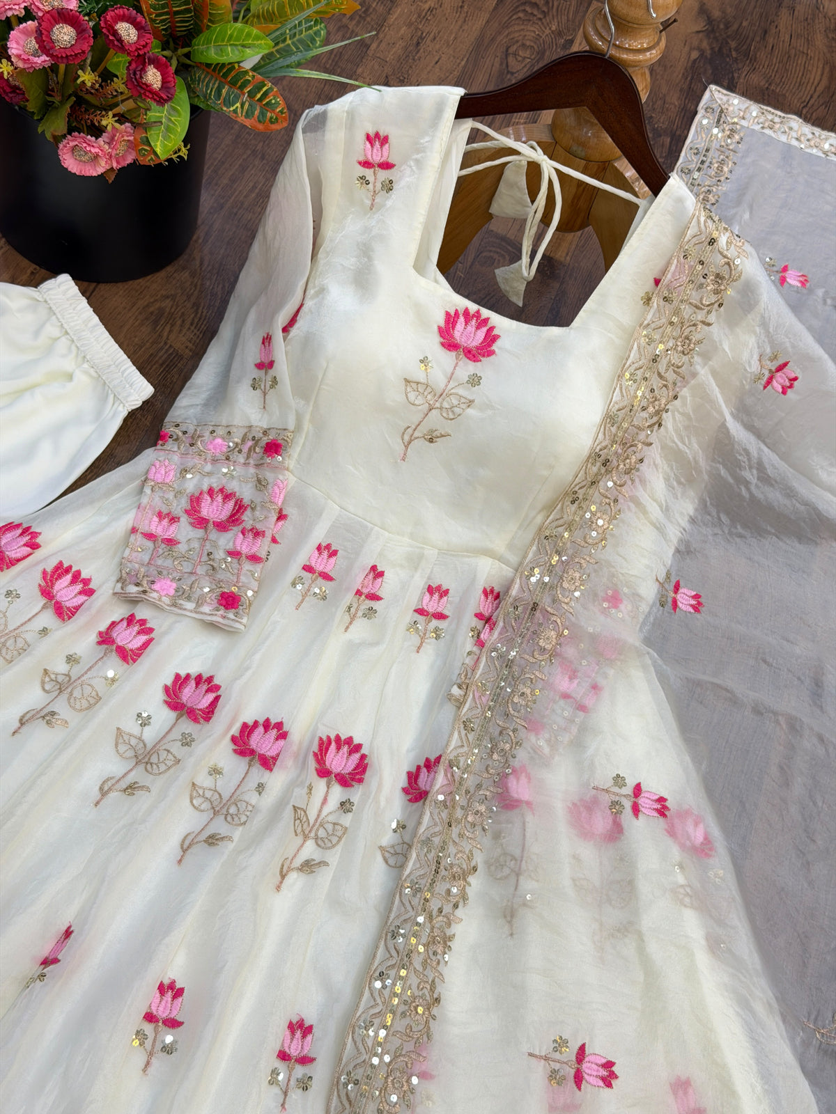 Off-White Fendi Silk Anarkali Gown Set - editorial studio full length calm standing model view showing complete set with all-over scattered hot pink blush lotus embroidery, wide three-row graduating lotus floral hem border with gold sequence scrollwork bands, square neckline and matching net dupatta with pink lotus butti held elegantly