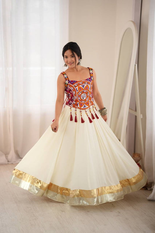 Ivory heavy rayon flared lehenga with gold-tone Lagdi patta lace hem, styled with a multicoloured embroidered real mirror work blouse and maroon tassels.