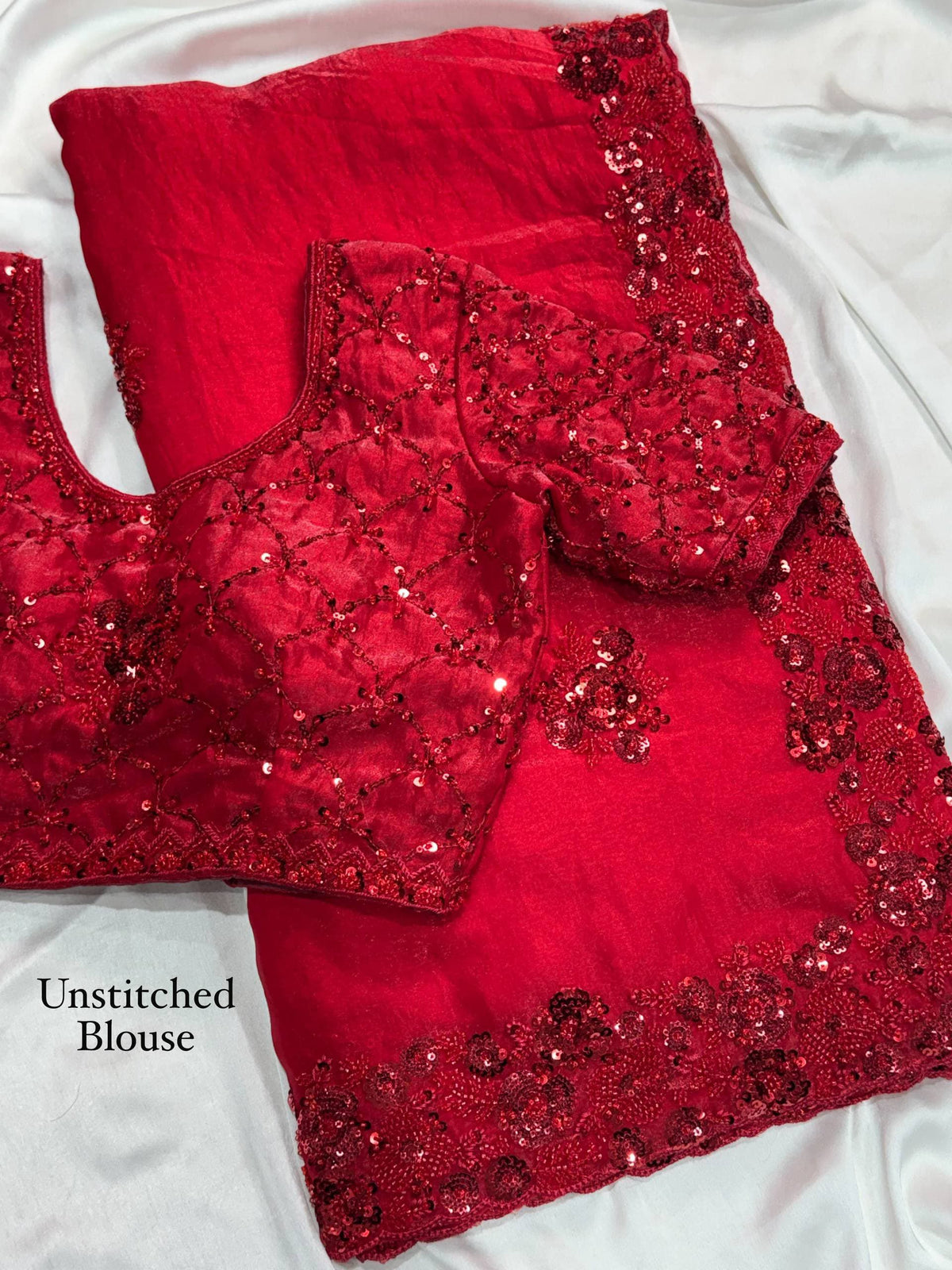 Crimson Red Fandy Satin Saree - flat lay close-up overhead showing unstitched blouse piece and saree pallu with scoop neckline cutout, full-coverage diamond lattice cord sequence pattern on blouse, scattered 3D raised red sequence floral bouquet butti on saree and blouse, and dense 3D sequence floral scallop cutwork border at saree edge