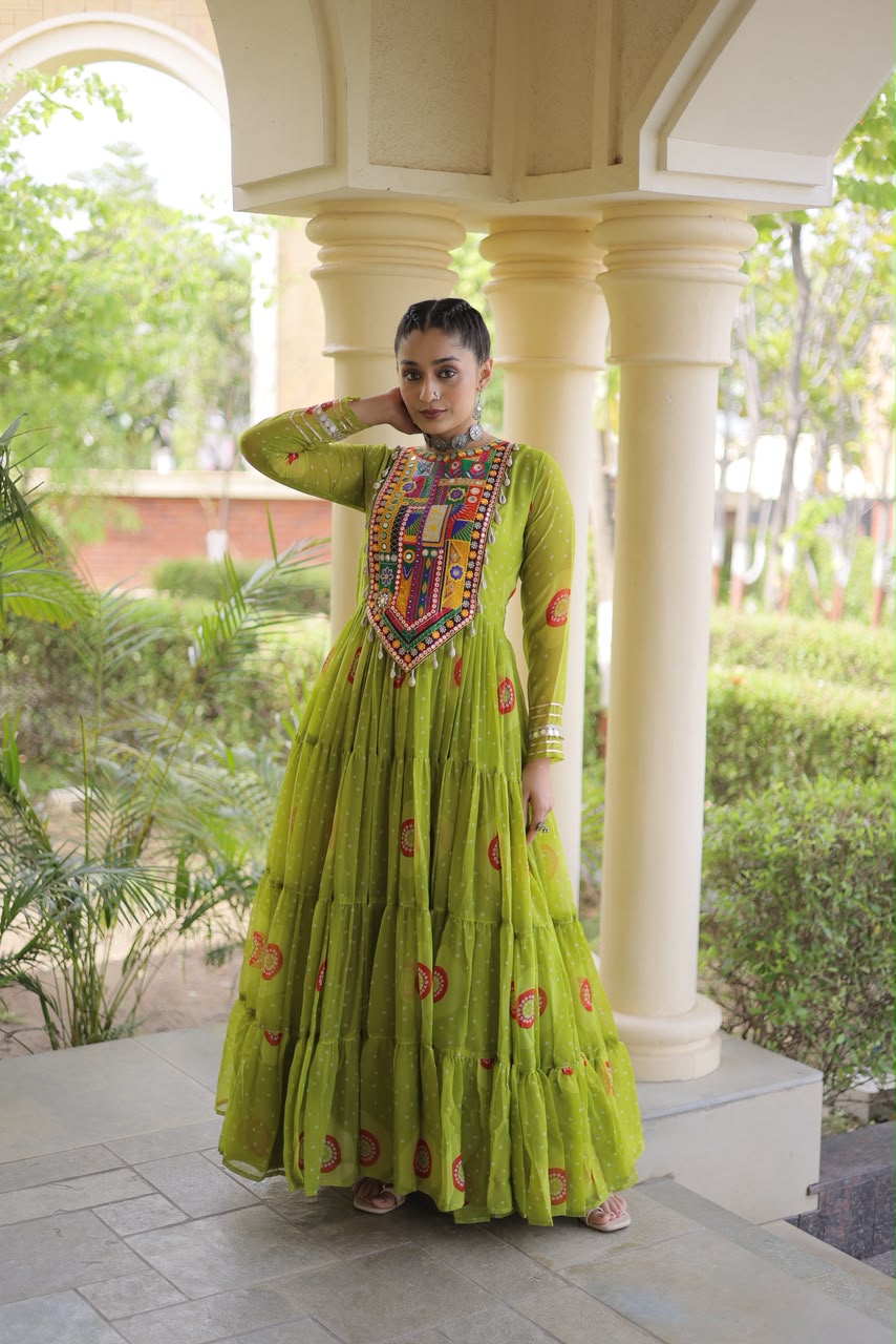 Lime Green Bandhani Faux Georgette Gown - outdoor haveli full length standing view showing complete 56-inch tiered gown with Kutchi patchwork yoke, all-over bandhani dot print with red orange yellow medallion and paisley motifs and 12-metre flair