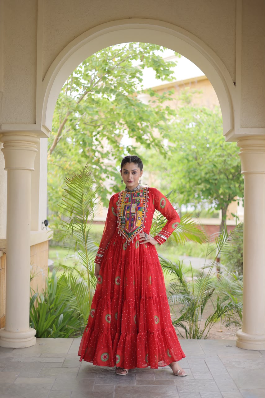 Red Bandhani Faux Georgette Gown with Kutchi Patchwork - outdoor haveli archway full length flowing view showing 12-metre flair with all-over bandhani dot print and circular medallion motifs