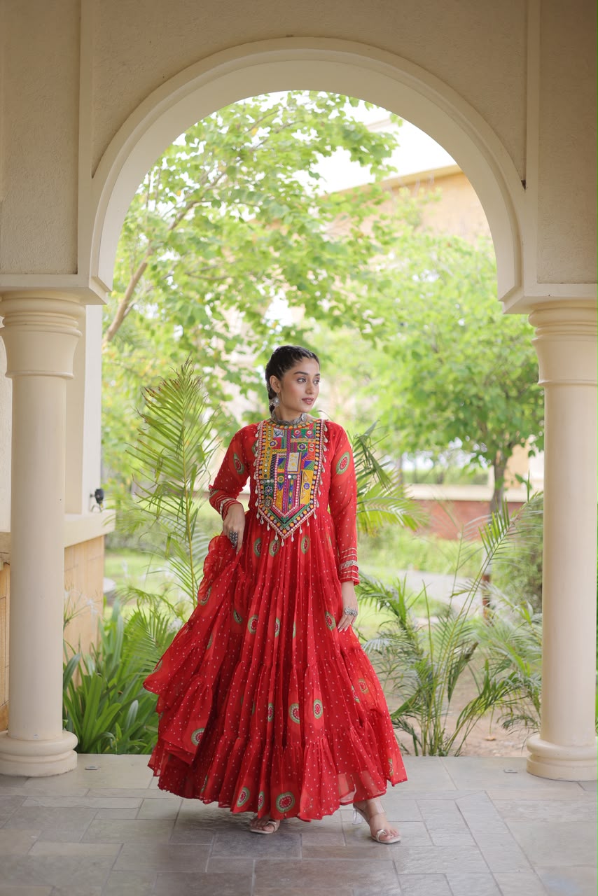 Red Bandhani Faux Georgette Gown - outdoor haveli archway full length standing view showing complete 56-inch gown silhouette with Kutchi patchwork yoke, bandhani body and full cotton-lined flair