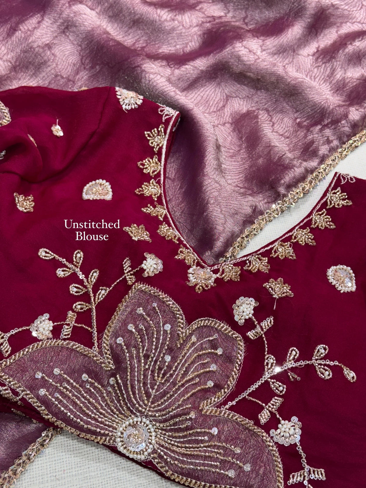 Close-up of wine red unstitched NC moss blouse fabric with large mauve floral applique and beads handwork beside rose mauve jacquard saree fabric.