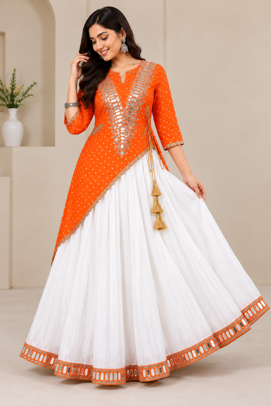 Orange Fox Georgette Asymmetric Kurti White Lehenga Set - heritage interior full length standing model showing silver mirror grid yoke, gold bandhani butti georgette, asymmetric hem with gold lace trim, mustard tassel latkan, and white full-flare lehenga with wide orange mirror arch hem border