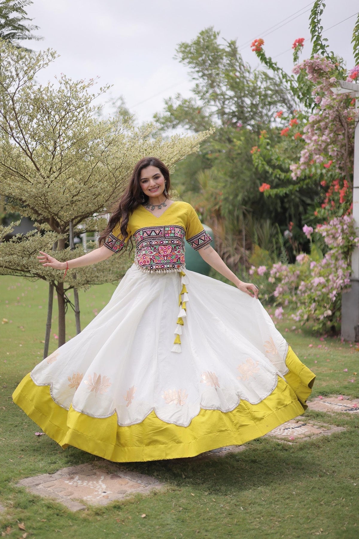 Fully stitched white Roman lehenga with lotus gota motifs, scalloped mirror lace edge and broad yellow hem, paired with a yellow Kutchi Gamthi embroidered choli.