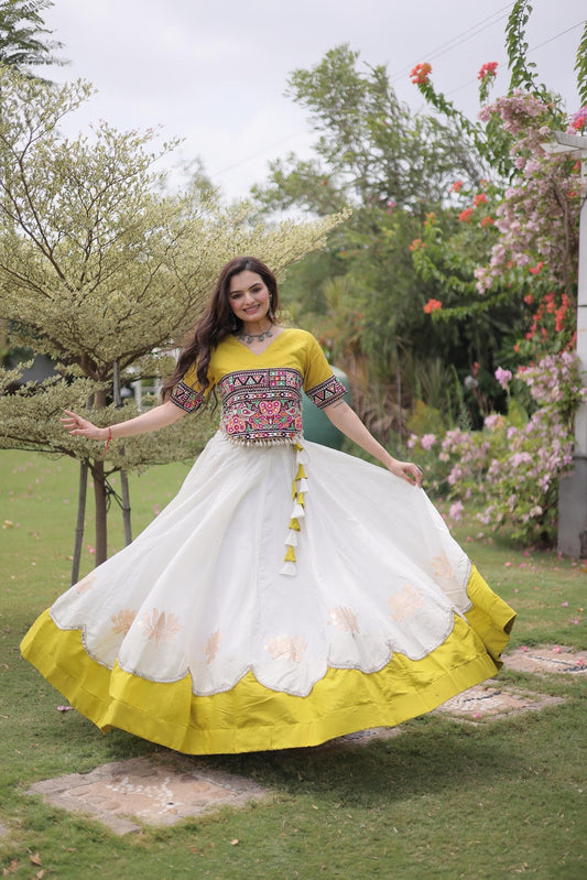 Fully stitched white Roman lehenga with lotus gota motifs, scalloped mirror lace edge and broad yellow hem, paired with a yellow Kutchi Gamthi embroidered choli.