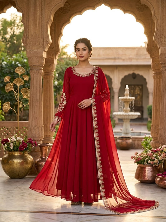 Deep Crimson Fox Georgette Anarkali Gown Set - Mughal palace courtyard full length standing model front view showing complete anarkali gown with round neckline gold zardozi moti border, dense gold zardozi floral bouquet moti vine embroidery on full sleeves shoulder to cuff, full flare crimson georgette floor-length gown body and matching crimson fox georgette dupatta with gold zardozi moti lace border draped over shoulder