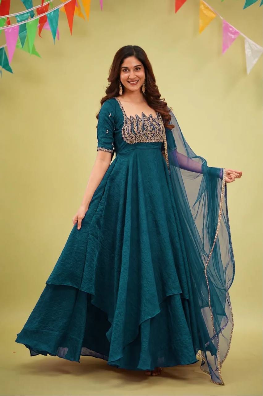 Teal blue Fandy crush silk Anarkali gown with sweeping asymmetric layers, elbow-length embellished sleeves and matching embroidered-border net dupatta.